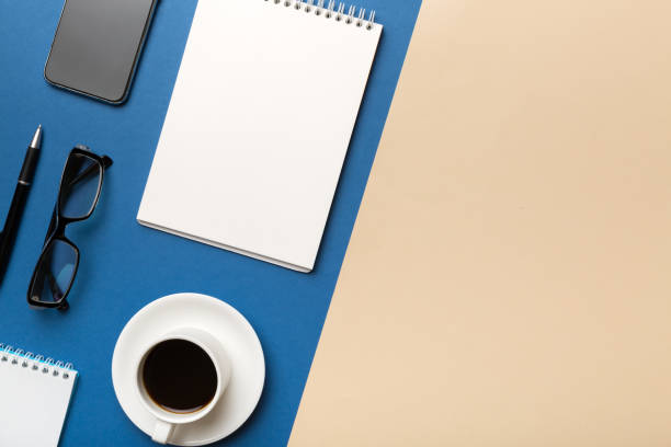 istock Modern office desk table with notebook and other supplies with cup of coffee. Blank notebook page for you design. Top view, flat lay 1390419941