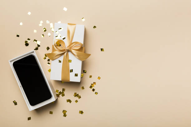 istock Opened gift box with gold ribbon and smartphone on color background, top view. Blank open box packaging mockup , Template for your design - branding mockup 1390419962