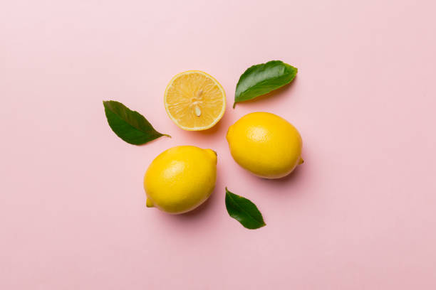 istock Many fresh ripe lemons with green leaves on colored background, top view, space for text 1390419965