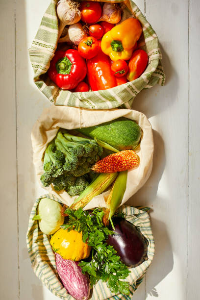 istock Top view assorted fresh vegetables in reusable cotton bags on table in the kitche in sunlight, groceries in textile Zero waste bags, Online grocery healthy shopping, vegan food. 1390420136