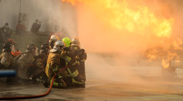 bombeiros usando extintor de incêndio tipo névoa de água do giro para combater com a chama de fogo do óleo para controlar o fogo para não se espalhar. bombeiro e conceito de segurança industrial. - bomba petrolífera - fotografias e filmes do acervo