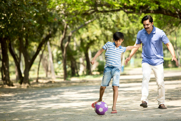 istock Father and son playing with ball at park 1390420306