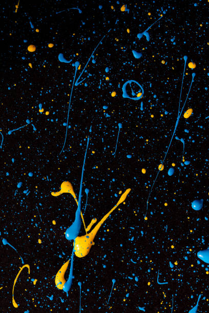 istock Blue and yellow paint drops on black canvas. 1390425608
