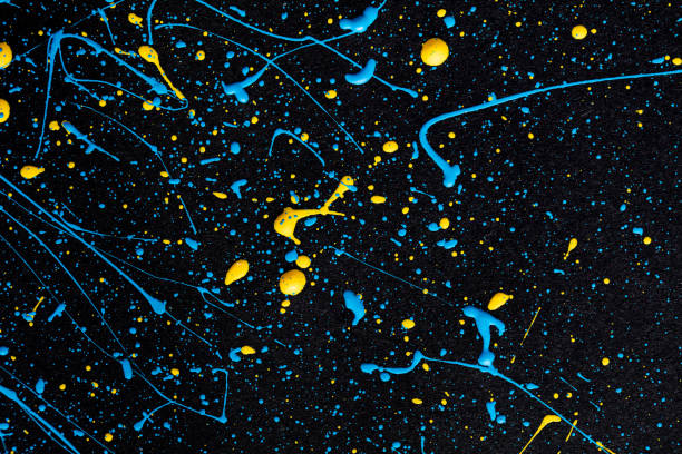 istock Blue and yellow paint drops on black canvas. 1390426053
