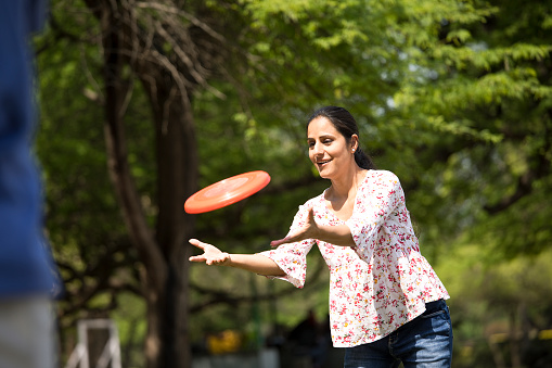 Cheerful couple having fun playing with frisbee disc at park