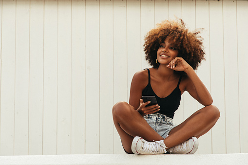 Pretty young afro woman using phone