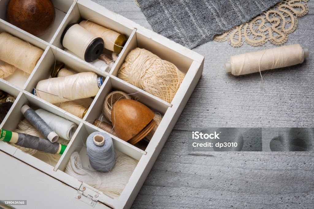 Sewing supplies on a wood table Set of sewing supplies on a grey table: sewing thread,  grey cloth, white box. With space for your logo or text Box - Container Stock Photo