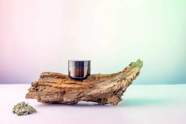 Photo of cosmetics container on the podium made of tree bark on a gradient background
