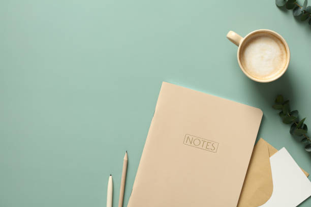 istock Minimal elegant office desk table with weekly planner, cup of coffee, eucalyptus leaves on green background. Flat lay, top view, copy space. 1390437331