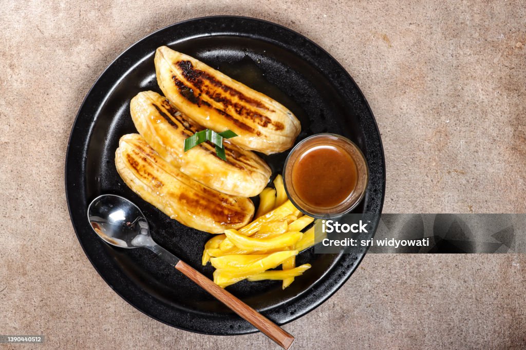Pisang Gapit or pisang Epe is Grilled banana with coconut brown sugar sauce Asian Food Stock Photo