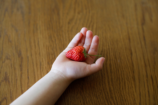 Child hand holding a strawberry