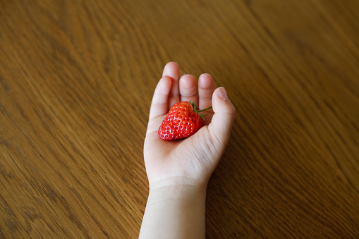 Child hand holding a strawberry