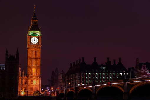 Big Ben of the Houses of Parliament London England UK at night striking midnight on new year's eve on Westminster Bridge which is a popular city landmark, stock photo with copy space