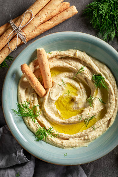 istock Vegan and fresh hummus with olives, grissini and herbs. 1390444613