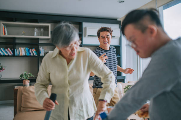 mehrgenerationen-asiatischer chinesischer mann, der mit seinem down-syndrom-sohn tanzt, singt mit großmutter, die am wochenende spaß im wohnzimmer hat - grandmother senior adult child multi generation family stock-fotos und bilder