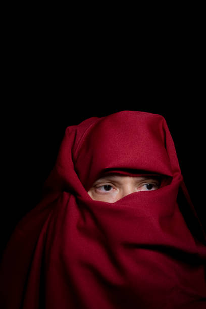 istock Man covered with red cloth against a black background. 1390445035