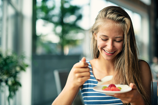 Teenage girl eating pieces of fruit.\nNikon D850