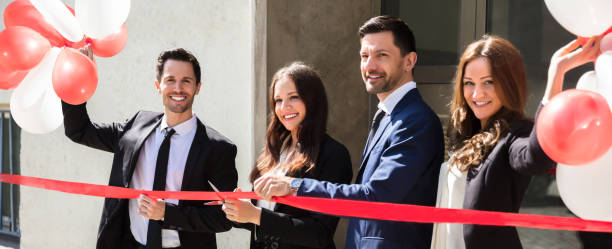 Businesspeople Cutting Red Ribbon Portrait Of Smiling Young Businesspeople Cutting Red Ribbon opening event stock pictures, royalty-free photos & images