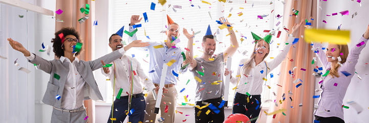 Excited Businesspeople Having Fun Raising Their Arms Among Party Confetti