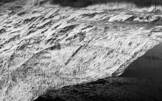 Black and white Beautiful Winter landscape image of Loch Achtriochan in Scottish Highlands with stunning reflections in still water