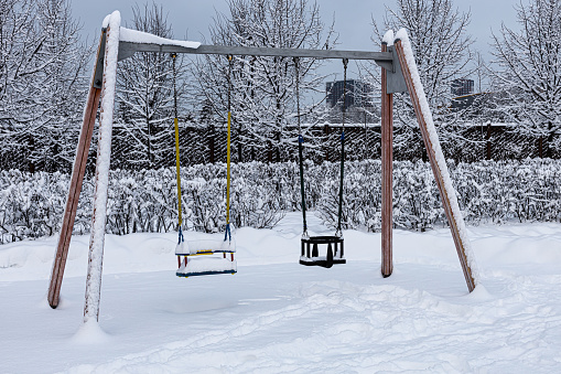 swing in the children's park covered with snow in winter