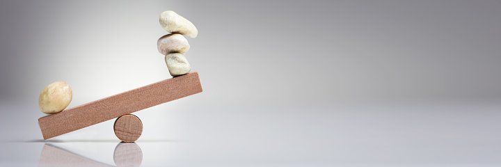 Pebble Stones Balancing On Wooden Seesaw Over The White Background