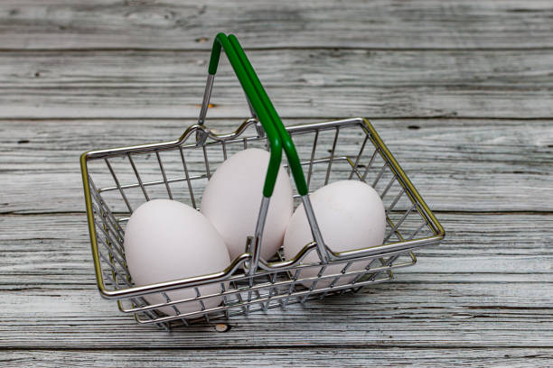 white egg lying in a miniature grocery basket