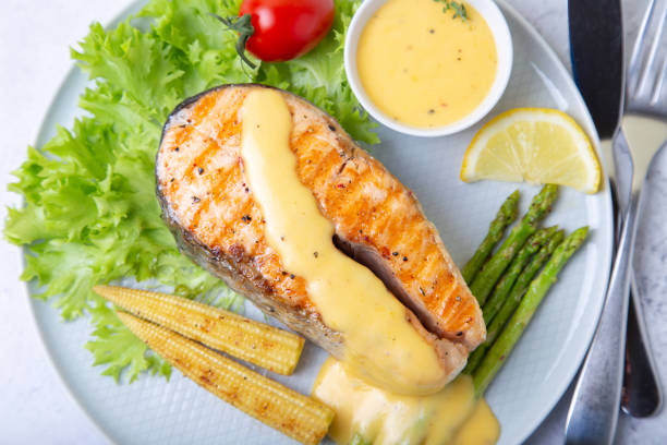 Grilled salmon with asparagus, mini corn and hollandaise sauce.  A traditional dish. Close-up, selective focus Grilled salmon with asparagus, mini corn and hollandaise sauce.  A traditional dish. Close-up, selective focus. hollandaise sauce stock pictures, royalty-free photos & images