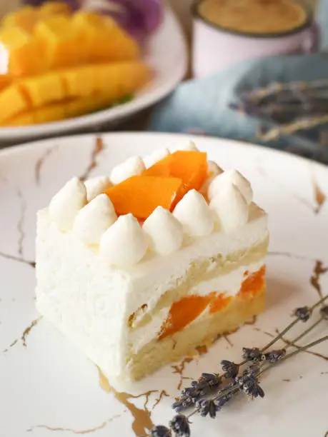 Photo of A piece of mango vanilla cream sponge cake with layer in a white plate