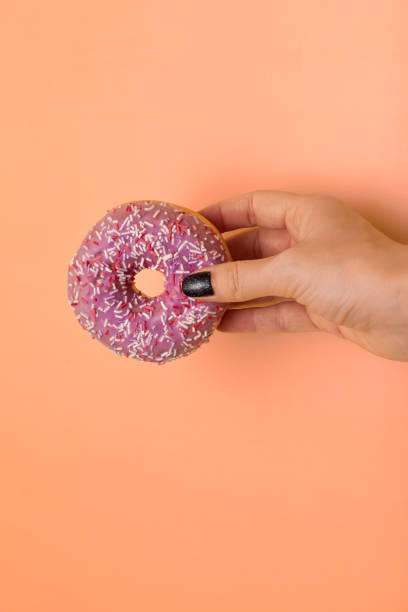 istock female hand holding donut on yellow green background 1390453611