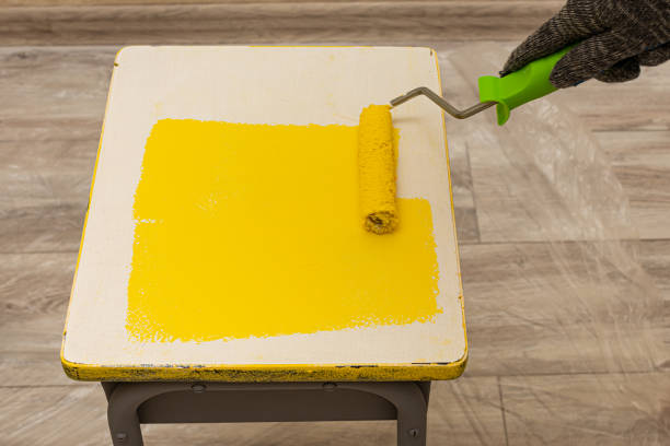 istock hand in motion paints a stool with yellow paint roller 1390454117