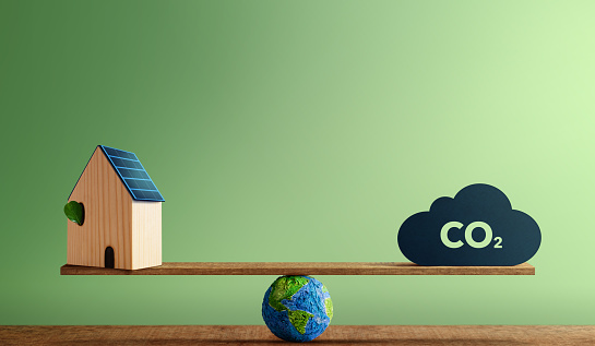 Conceptos neutros en carbono. Energía limpia. Energía Verde. Equilibrio del globo entre una casa solar en la azotea y el icono de CO2. Recursos Sostenibles, Cuidado del Medio Ambiente photo