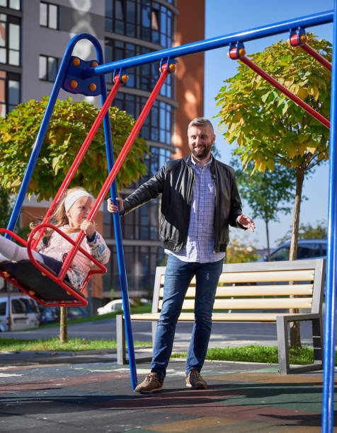 istock Dad swinging adorable daughter on swing at playground. 1390468169