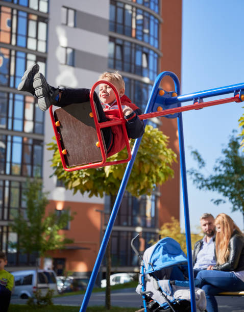 istock Joyful boy swinging on swing with parents behind. 1390468201