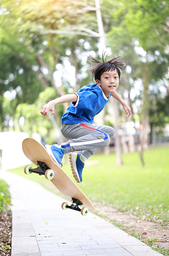 Asian teenage boy skateboarding outdoors