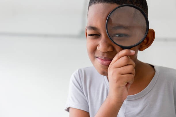 istock Smiling kid boy playing cheerfully with magnifying glass 1390472293
