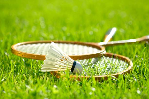 zwei badmintonschläger und ein federball liegen auf dem grünen gras. - badmintonschläger stock-fotos und bilder