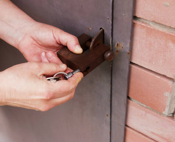 istock Women's hands open a rusty lock with keys. Lock on a metal door. Security. 1390476525