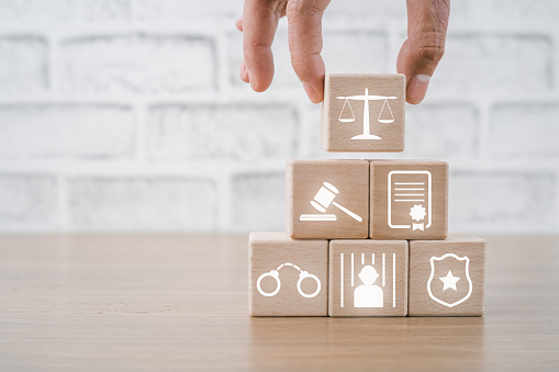 Person hand holding law icon on wooden cube with copy space, terrorism, crime, judgment, verdict, justice and law concept