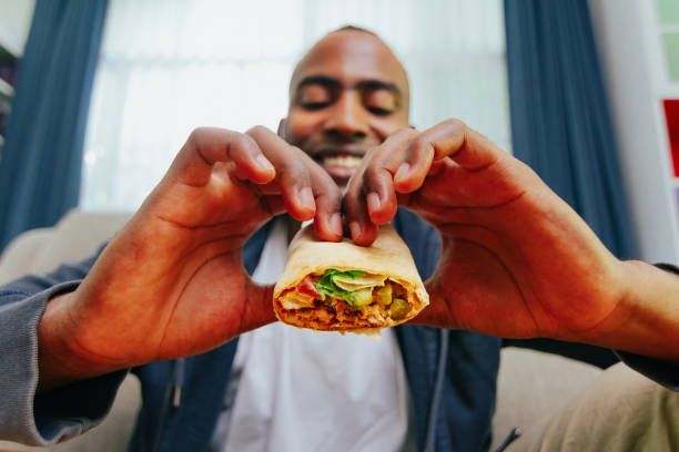 치킨 부리토를 먹는 남자, 와이드 샷 pov. - burrito 뉴스 사진 이미지