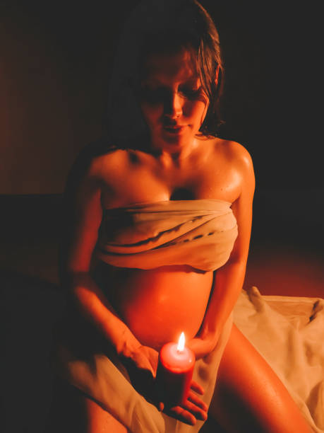 młoda kobieta w ciąży w białym welonie z płonącą świecą - human pregnancy abdomen naked human hand zdjęcia i obrazy z banku zdjęć