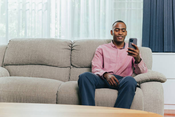 istock Man using mobile phone in living room. 1390482047
