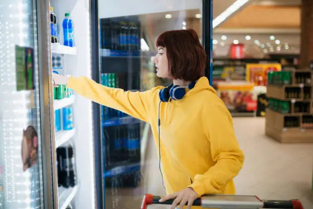 Photo of Side view of a young Caucasian woman doing her shopping in supermarket