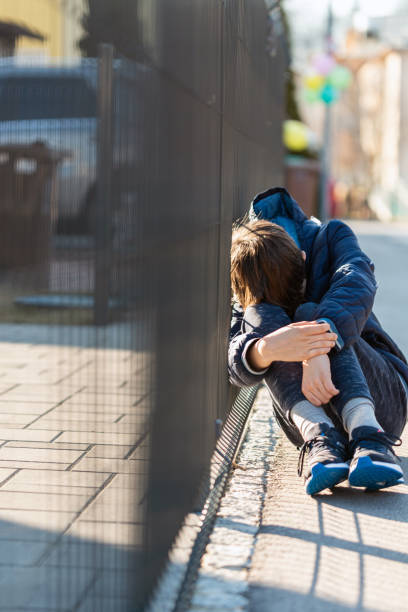 istock Sad boy sitting and crying on street 1390483019