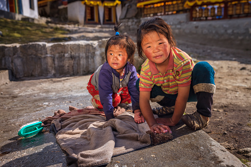 Two Sherpa little girls washing clothes in the her village, Buddhist monastery on the background, Mount Everest National Park, Nepal. This is the highest national park in the world, with the entire park located above 3,000 m ( 9,700 ft). This park includes three peaks higher than 8,000 m, including Mt Everest. Therefore, most of the park area is very rugged and steep, with its terrain cut by deep rivers and glaciers.