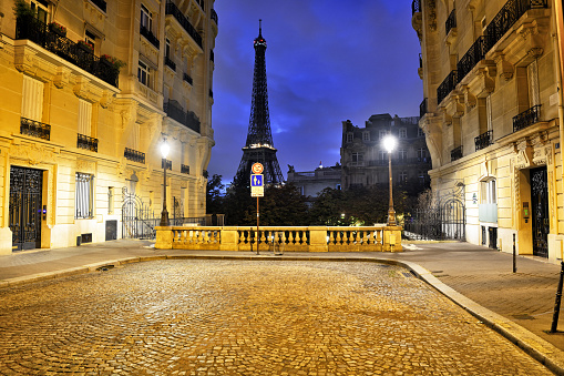 Eiffel tower between the old buildings in the street of Paris, France