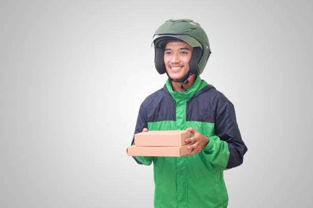 Asian online courier driver delivering package and box for customer Portrait of Asian online courier driver wearing green jacket and helmet delivering package and box for customer. Isolated image on white background vietnamese man taxi motorbike driver stock pictures, royalty-free photos & images