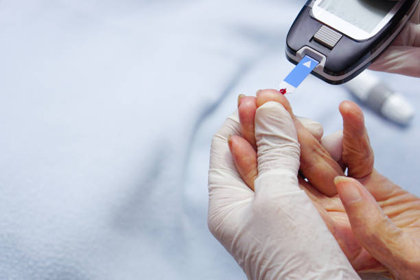 врач надевает перчатки, используя ланцет на пальце пациента. - blood sugar test стоковые фото и изображения