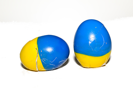 Two cracked shell Easter eggs with Ukrainian flag color blue and yellow color on white background.