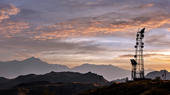 Landscape with cell phone communication tower with sunset and rocky desert mountains near Phoenix Arizona in background